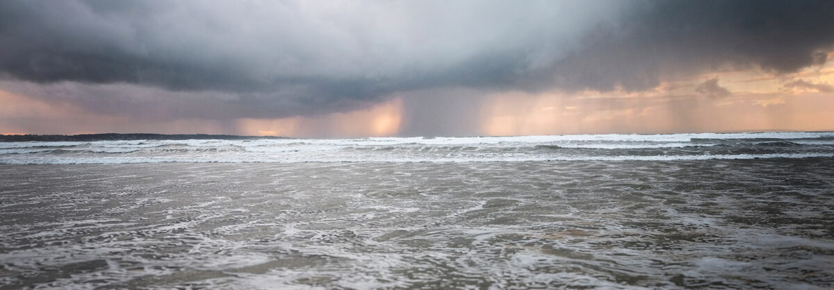 Coucher de soleil flamboyant à travers la pluie sur la plage de Sainte-Anne-la-Palud en baie de Douarnenez.