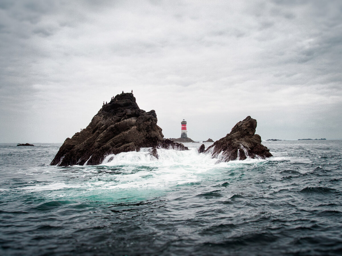 Le phare des Pierres Noires isolé en pleine mer d'Iroise sur son socle de roche noire.